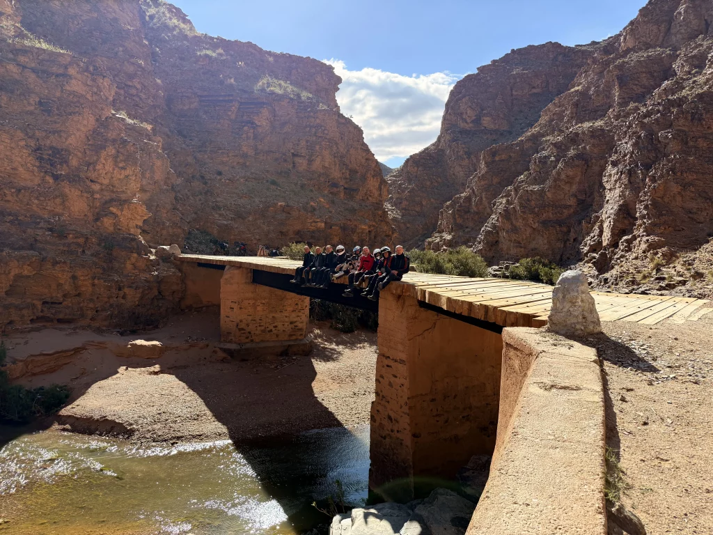 Grupo de motoristas sentados en un puente de madera en las minas de aoulih